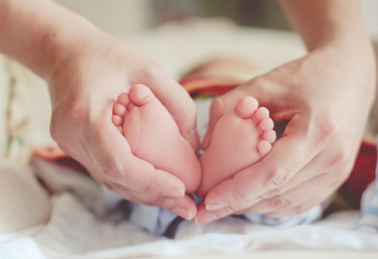 Woman holding feet of baby, used in post about Generation Prime