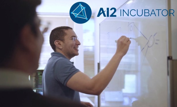 Two people work at a whiteboard with the AI2 logo overlaid.