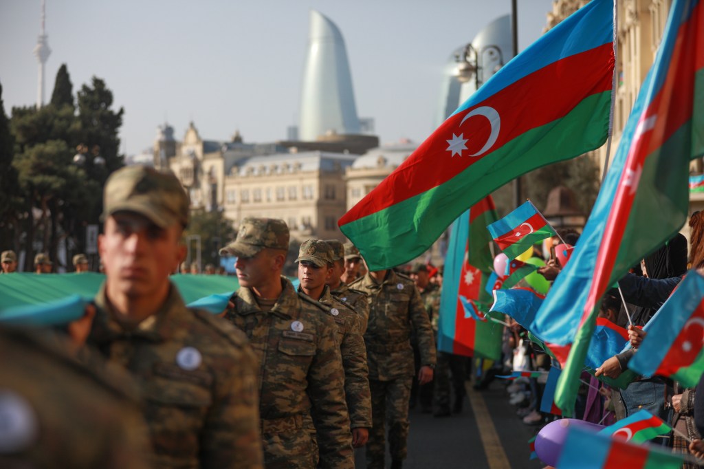 Azeri service members carry a giant flag during a procession marking the anniversary of the end of the 2020 military conflict over Nagorno-Karabakh breakaway region on November 8, 2021 in Baku, Azerbaijan.