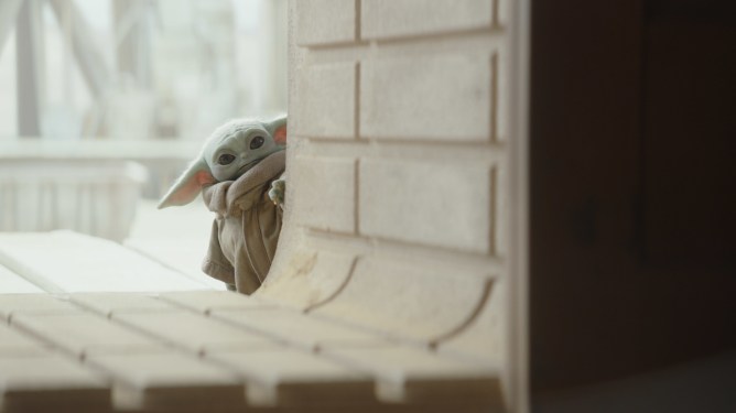 An image of Baby Yoda peaking out from a wall
