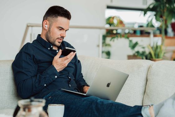 Man sitting on couch holding open laptop
