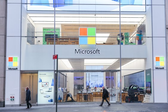 People walk past a Microsoft store entrance with the company's logo on top in midtown Manhattan