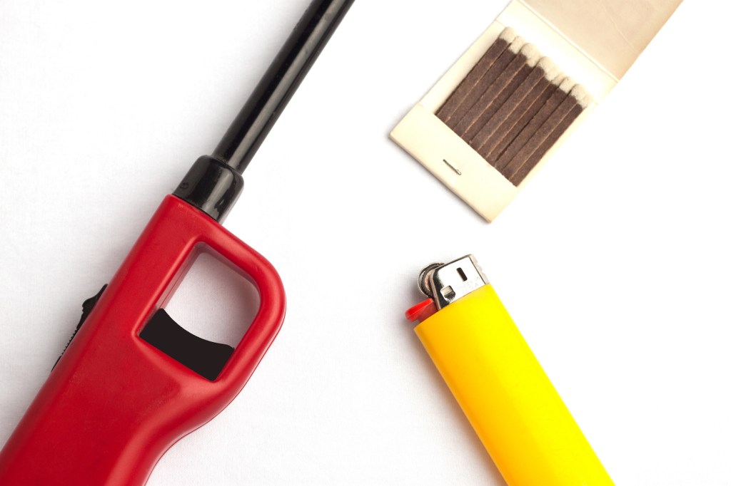 Variety of lighters against a white background including a gas lighter, disposable lighter, and matches