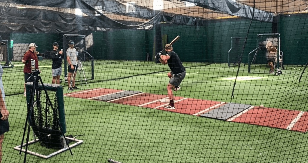 batter hitting baseballs in a batting cage