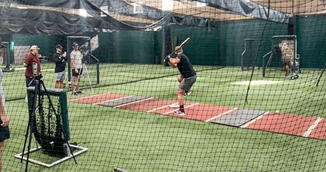 batter hitting baseballs in a batting cage