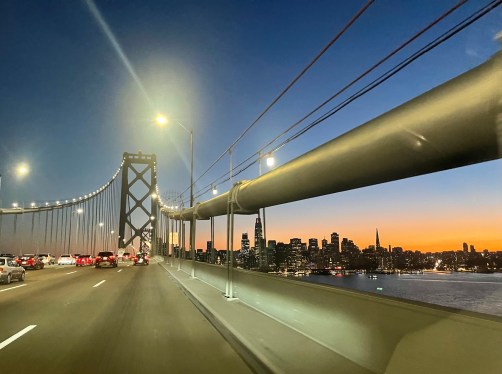 Driving west on the Bay Bridge toward San Francisco at sunset.