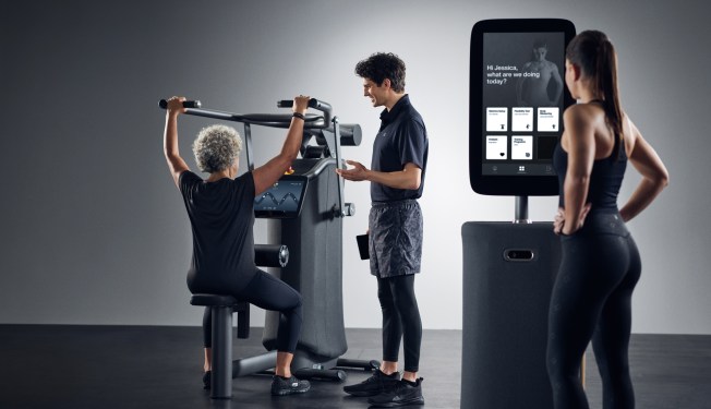 person lifting weights using EGYM, with two onlookers
