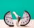 Analog wall clock being split in half by an axe, wood surface, green studio background