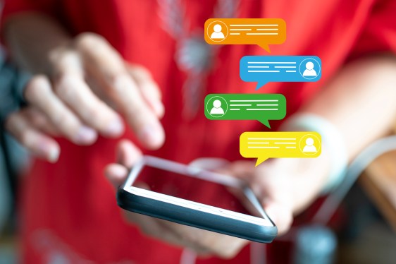 Group of message bubbles coming out of a mobile phone in a woman's hand.