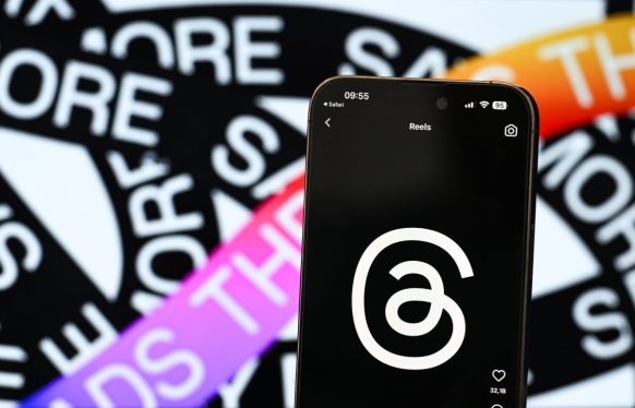 In this photo illustration, logo of Threads is displayed on a mobile phone screen in front of a screen