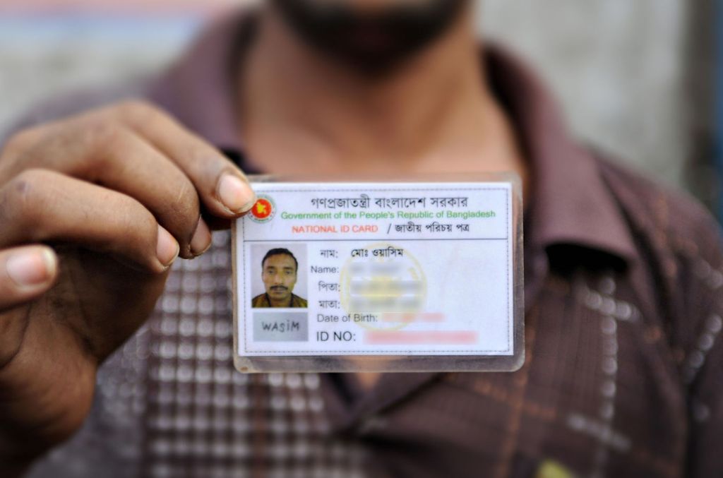 A Bangladeshi man holds up his national ID card (which we have blurred)