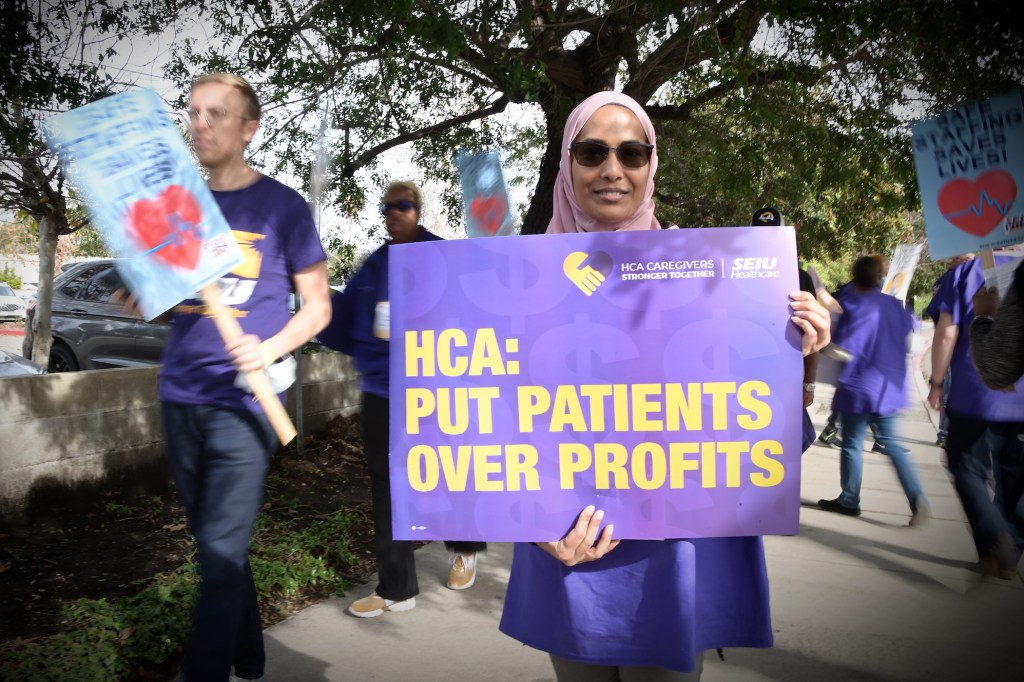 A protester holding up a sign that says "HCA: put patients over profits" during a January 2023 march outside an HCA facility.