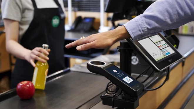 Person holding palm over payment scanner at grocery store checkout