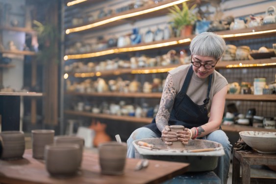 Senior woman artist making clay bowl on pottery wheel in pottery studio, used in post about Markato