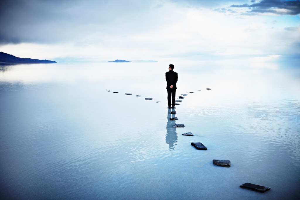 Man standing on stones that fork in two directions.