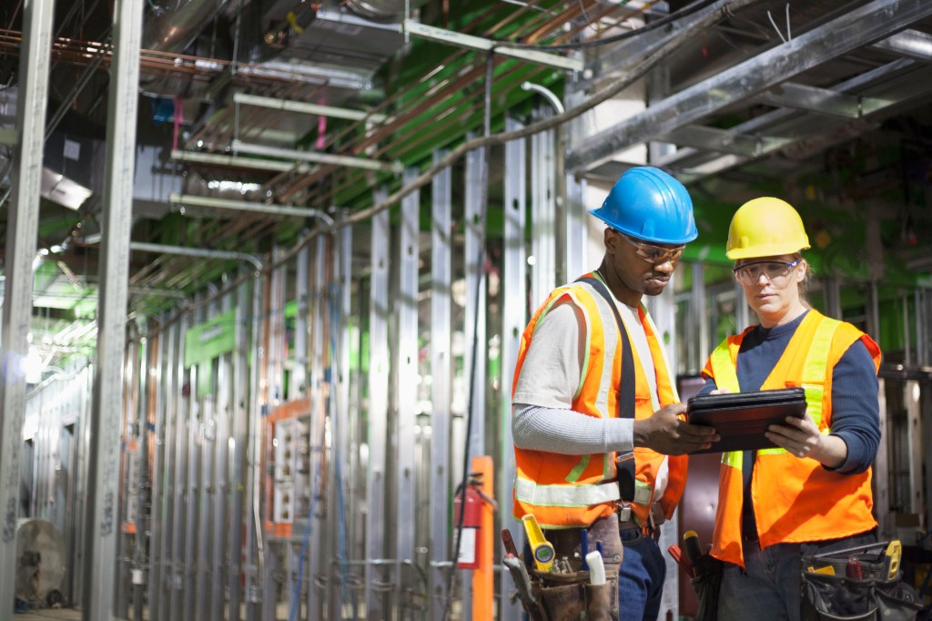 Workers using tablet computer on construction site