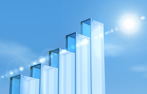 Glass pillars forming a growth bar graph against a bright blue sky background.
