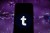 Photo illustration of a Tumblr logo displayed on a smartphone with a COVID 19 sample image in the background.