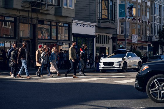 waymo jaguar i-pace at crosswalk with people walking in front