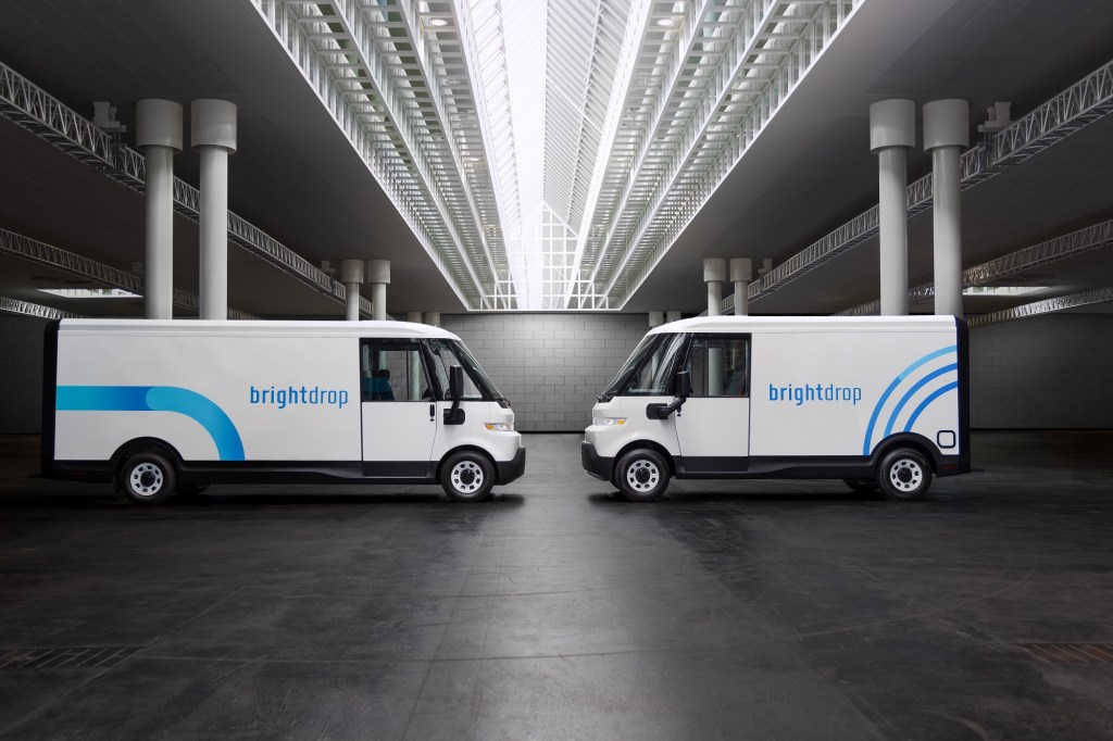 Two white and blue commercial vans, the one on the left is larger, are parked facing each other.