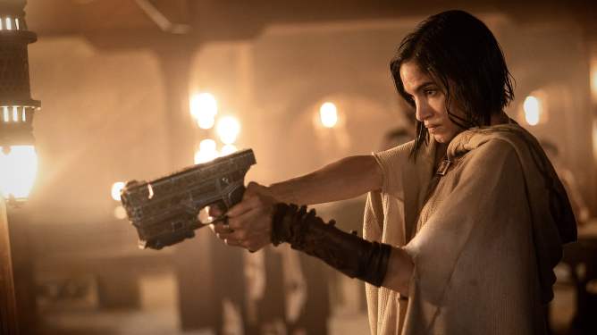 Scene from Rebel Moon; woman pointing hand-held weapon