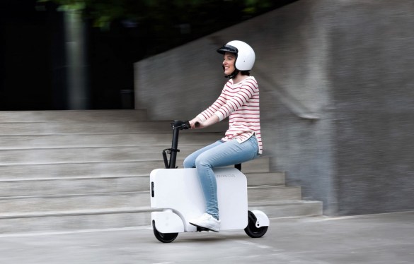 Woman riding the new Honda Motocompacto e-scooter in a city
