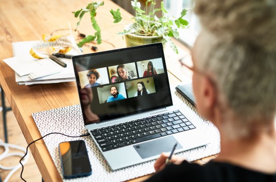 Businesswoman seated at laptop on wooden desk during online meeting
