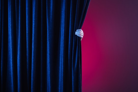 Midsection of woman holding curtain while standing against curtain