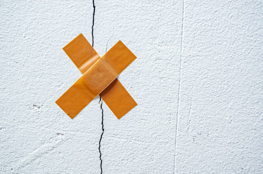 The band-aid plaster on a crack in the home wall. Cracks in the wall caused by ground shrinkage, the need to repair the building, renovation. Symbolic image