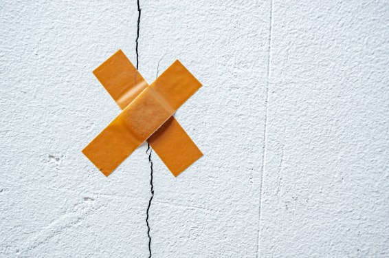 The band-aid plaster on a crack in the home wall. Cracks in the wall caused by ground shrinkage, the need to repair the building, renovation. Symbolic image