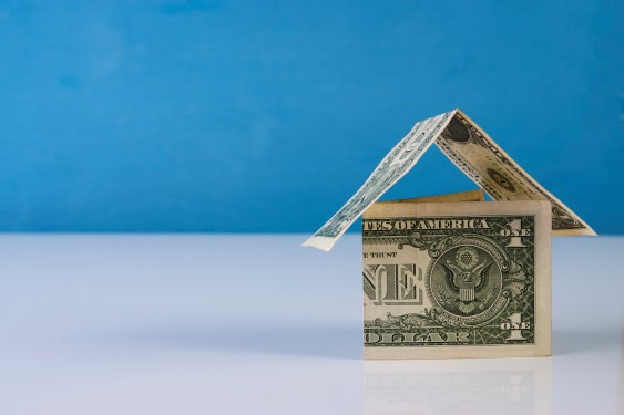 Home made from dollar notes on blue and white background, close-up. Mortgage concept