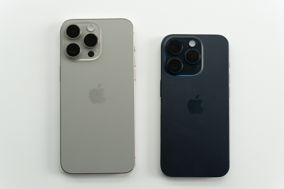 The natural titanium iPhone 15 Pro Max, and the blue titanium iPhone 15 Pro side-by-side, face down on a table