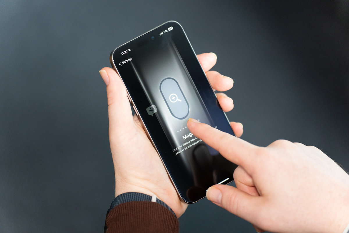 iPhone 15 Pro Max in natural titanium, being held, showing the display and Action button customization interface