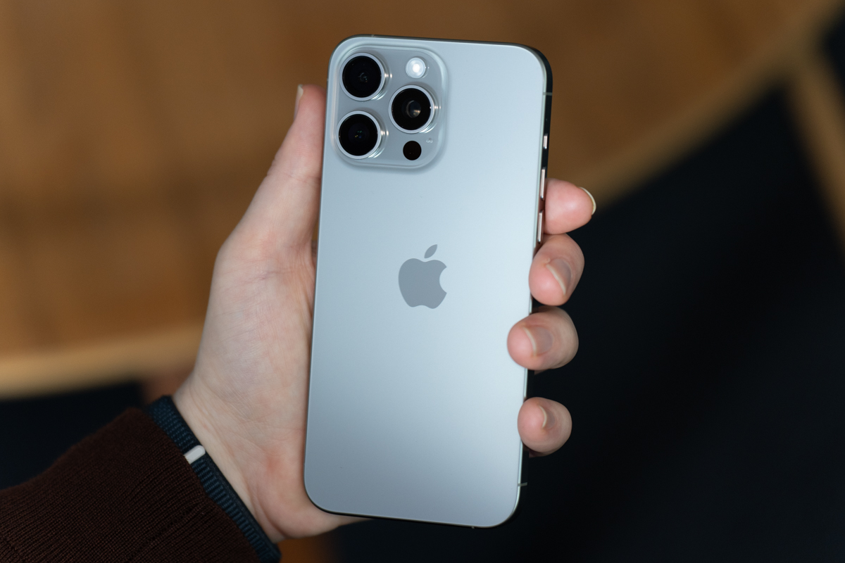iPhone 15 Pro Max in natural titanium, being held, showing the back of the phone