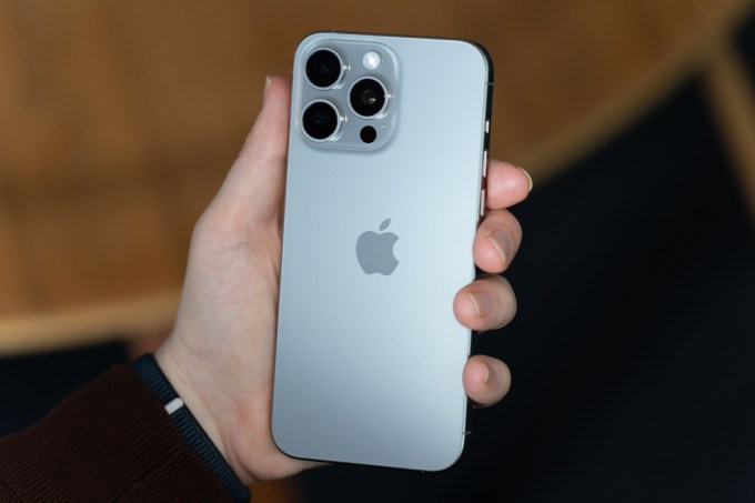 iPhone 15 Pro Max in natural titanium, being held, showing the back of the phone