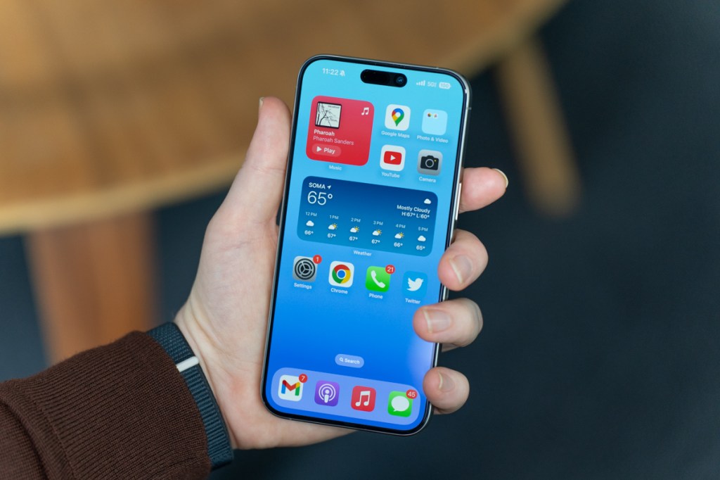 iPhone 15 Pro Max being held, display on showing the Home Screen