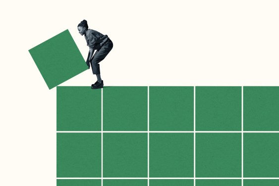 Full length side view of young woman building grid with green blocks against white background