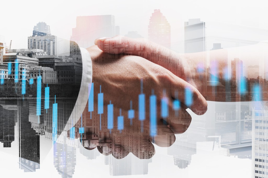 Business people shaking hands with financial chart in foreground and city in the background.