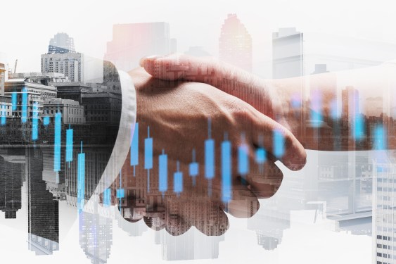 Business people shaking hands with financial chart in foreground and city in the background.