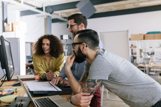 A team of startup co-workers gathered around a computer
