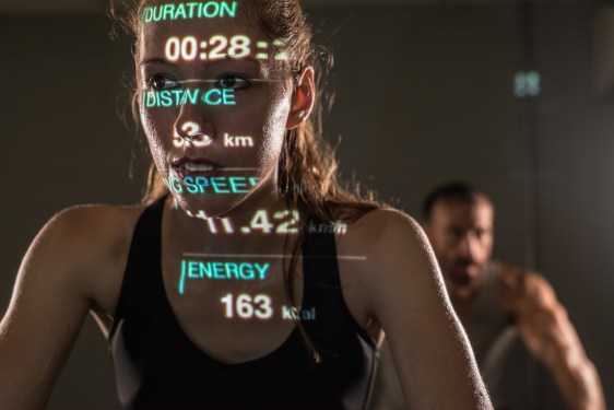 Woman on exercise bike with data overlaying her about her performance.