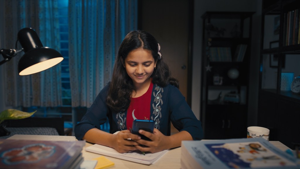 A Bangladeshi female student holding an iPhone to participate in a live class by 10 Minute School