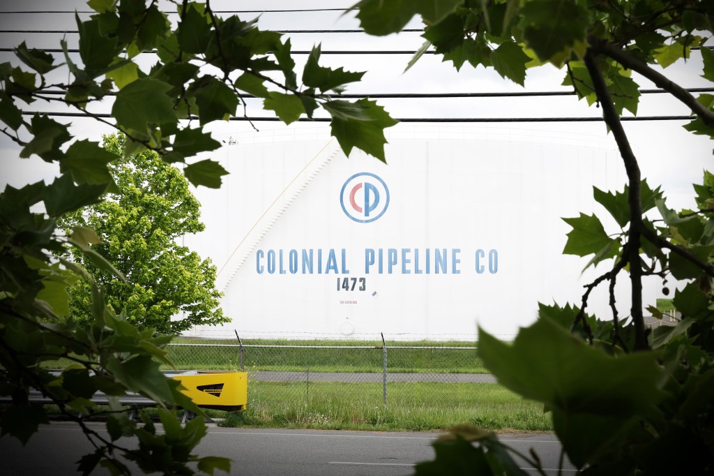 a photo of a Colonial Pipeline gas storage depot in between leaves near a highway