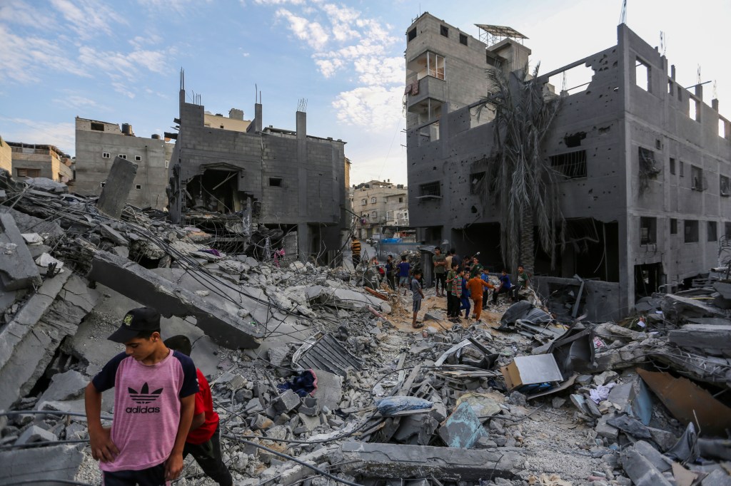 KHAN YUNIS, GAZA - OCTOBER 27: People search through buildings that were destroyed during Israeli air raids in the southern Gaza Strip on October 27, 2023 in Khan Yunis, Gaza. Two weeks after a deadly Hamas attack in southern Israel that sparked a retaliatory siege of Gaza, in which thousands have died and hundreds of thousands have been displaced, aid trucks have started entering the Palestinian territory via Egypt carrying food, water and medicines. The UN agency UNRWA, or the Relief and Works Agency for Palestine Refugees, says the initial aid is a "drop in the ocean" of what is needed. (Photo by Ahmad Hasaballah/Getty Images)