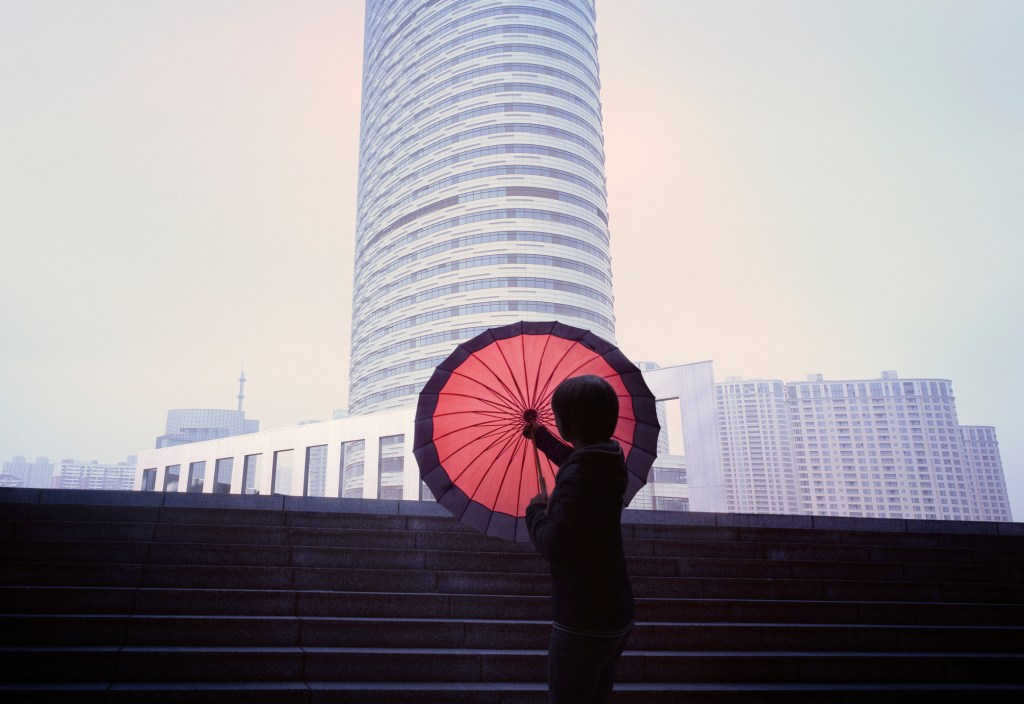 Women with red umbrella in front of city skyline