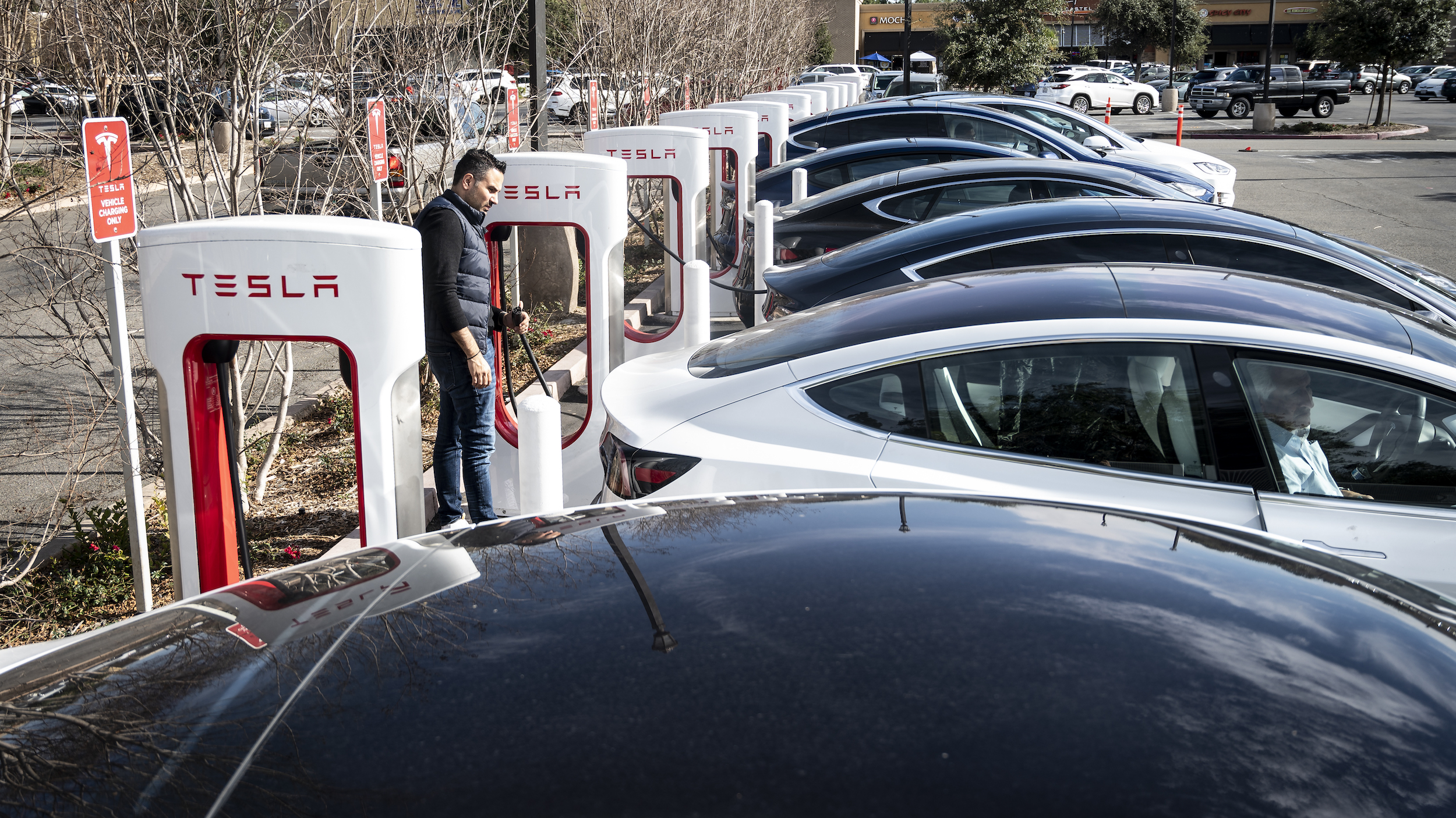 A tesla supercharger station filled with electric cars.