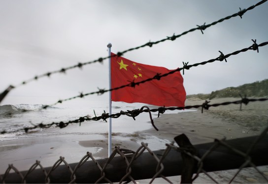 China flag flying behind barbed wire