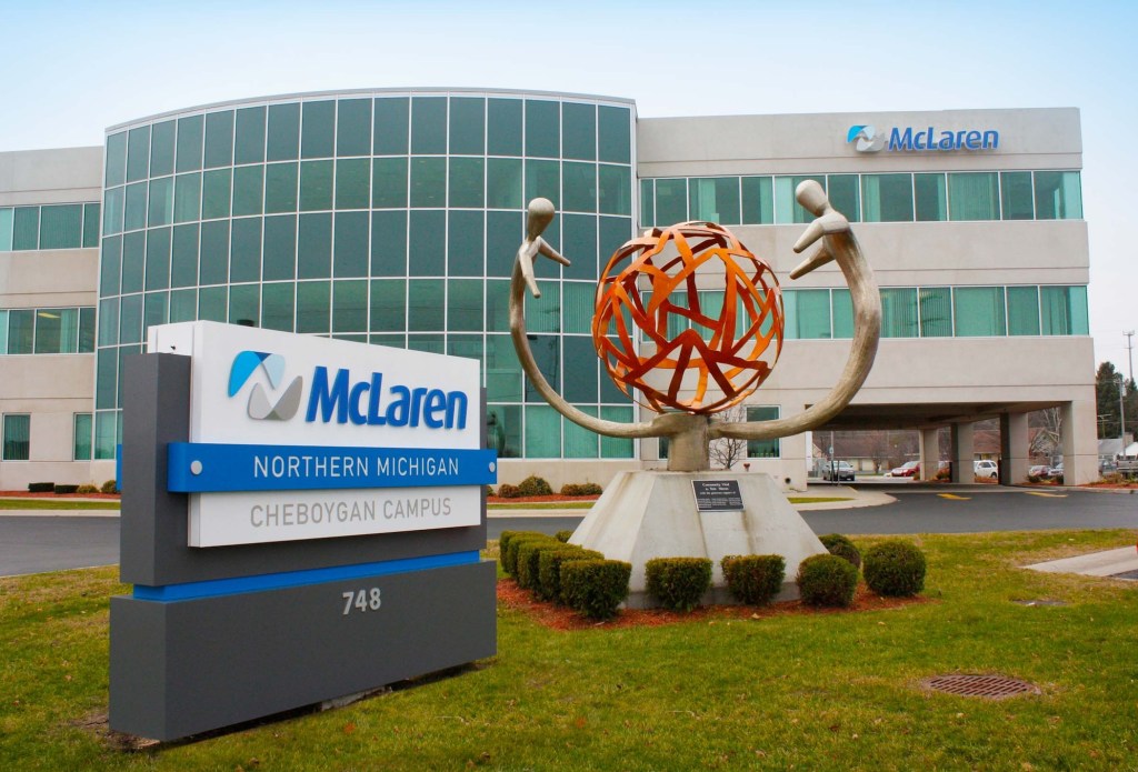 a photo of outside McLaren's hospital campus, showing a building in the background with a sign outside with McLaren's logo