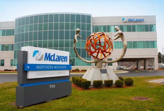 a photo of outside McLaren's hospital campus, showing a building in the background with a sign outside with McLaren's logo