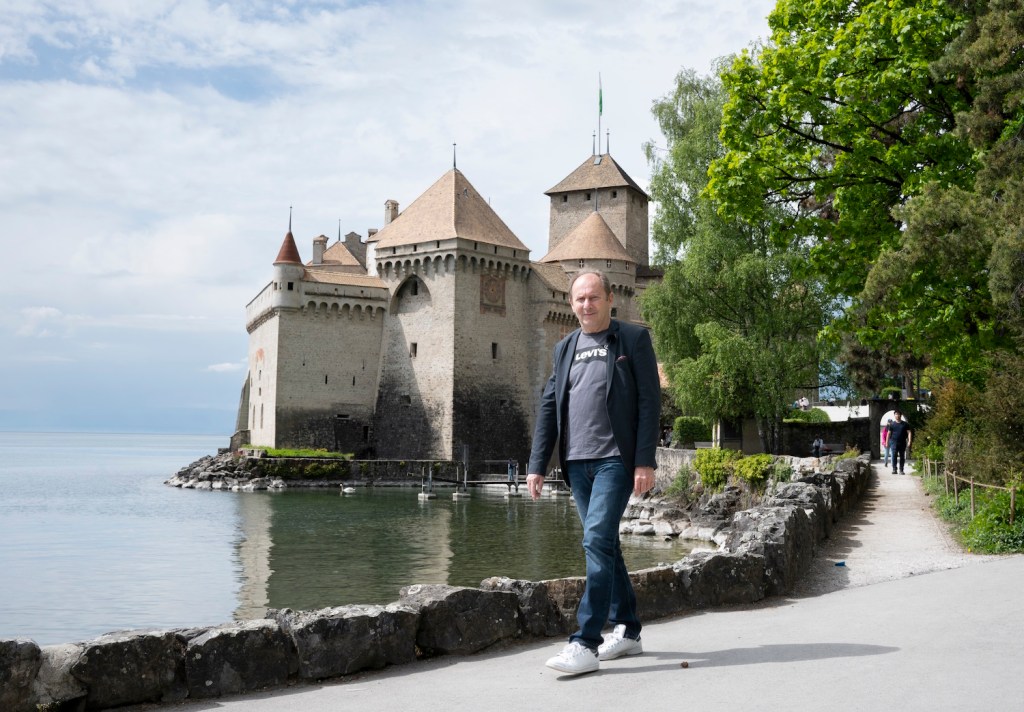 Man walking lakeside, castle in background